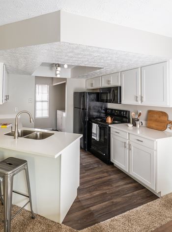 A kitchen with white cabinets and a black refrigerator.